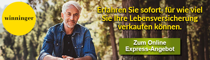 Ein lächelnder Mann mit Jeanshemd sitzt vor einem Waldrand